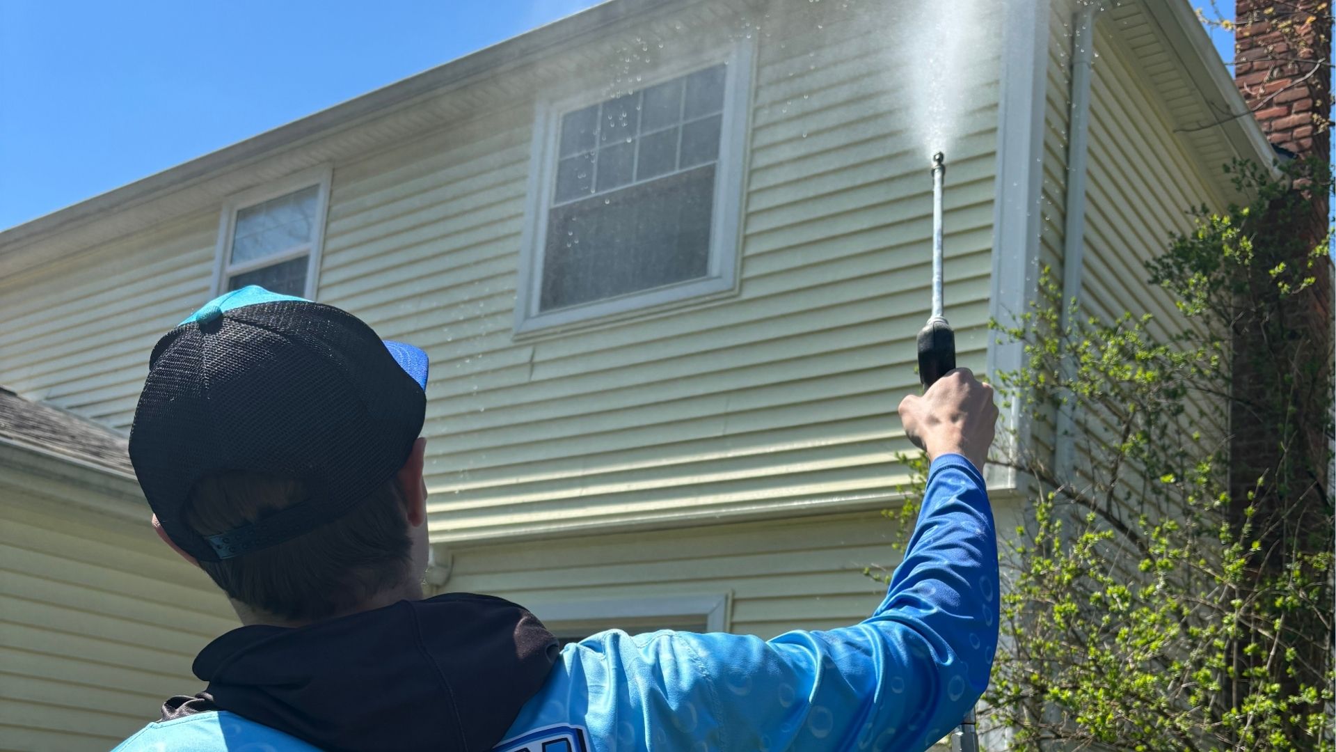 professional cleaning siding of white home