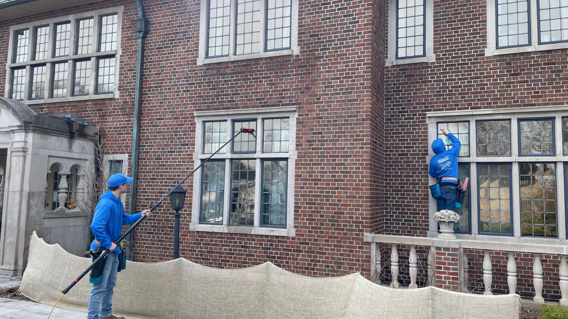 professionals cleaning windows on brick building